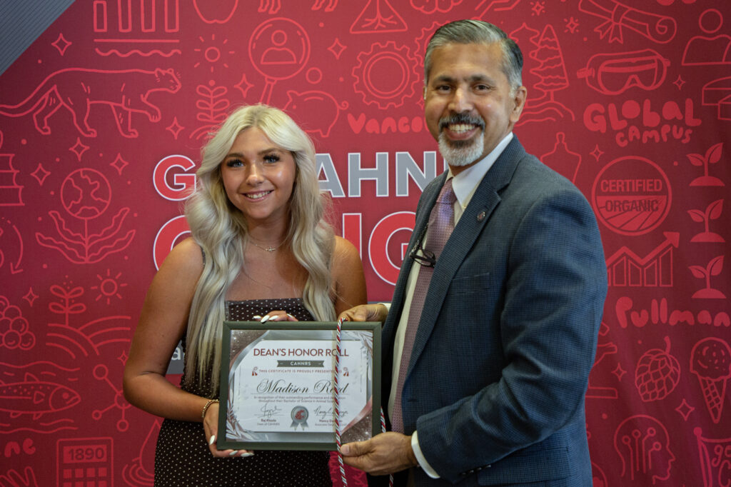 Dean Khosla handing over "Dean's Honor Roll" certificate to a student.