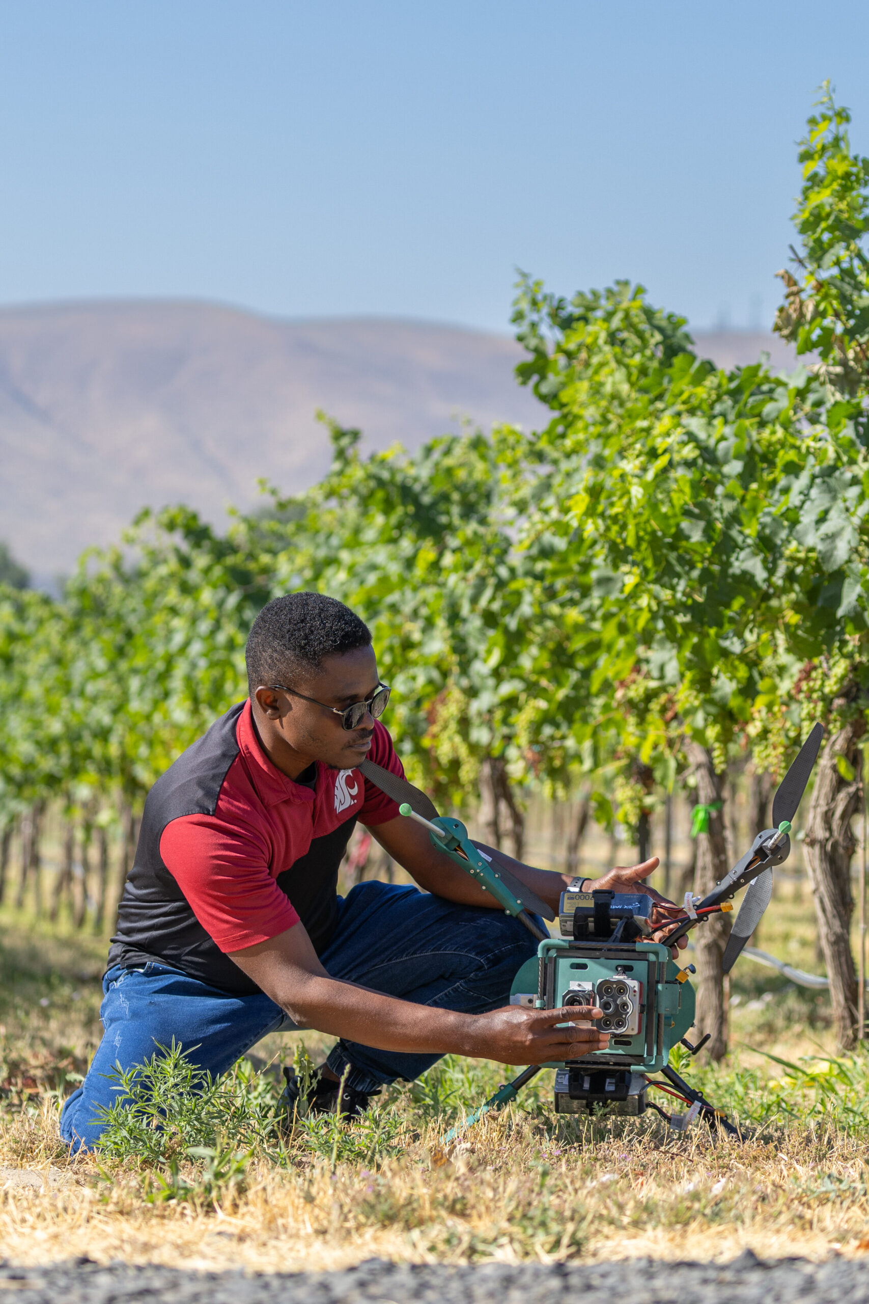 WSU Student in an orchard working on a drone