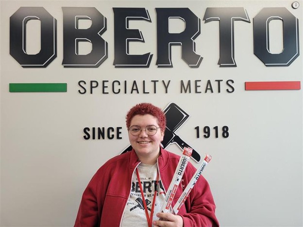 Hallie Simpson standing in front of an Oberto Specialty Meats sign.
