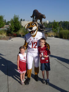 Tessa and Wesley Hausken pose with the furry version of WSU mascot Butch as the bronze incarnation looks on.