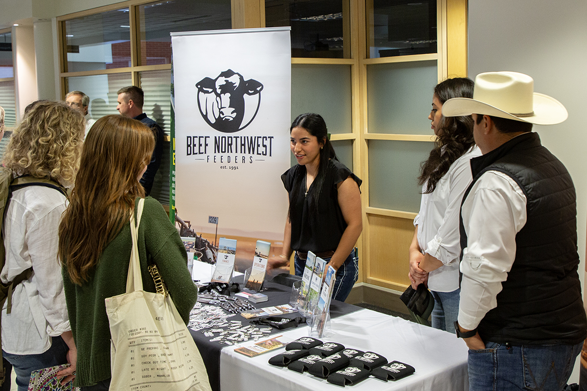 A representative of Beef Northwest at a booth in the CAHNRS Networking Night fair talks with a CAHNRS student about opportunities in their business.