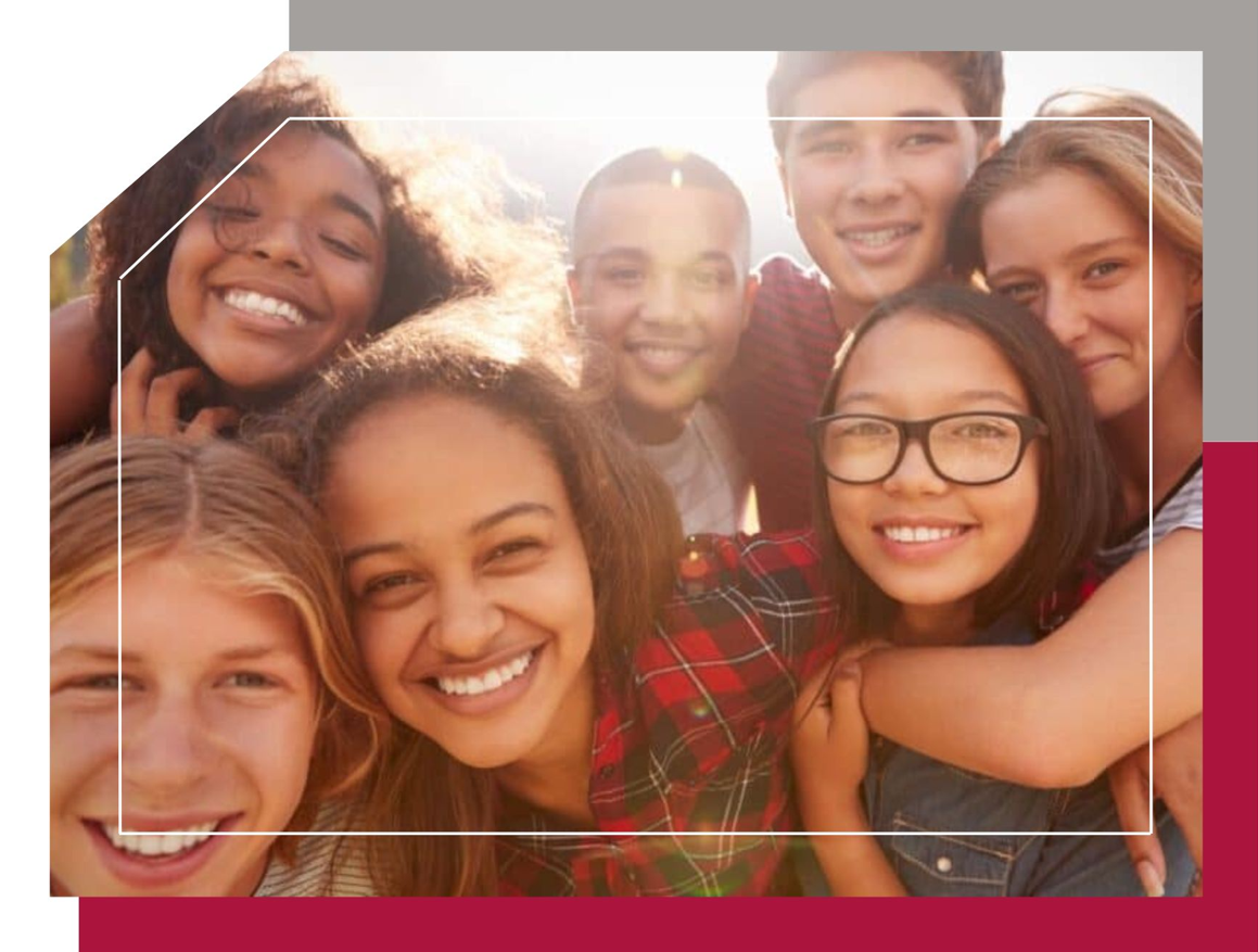 Students huddle with the sun peaking through behind them, smiling and looking empowered and at peace
