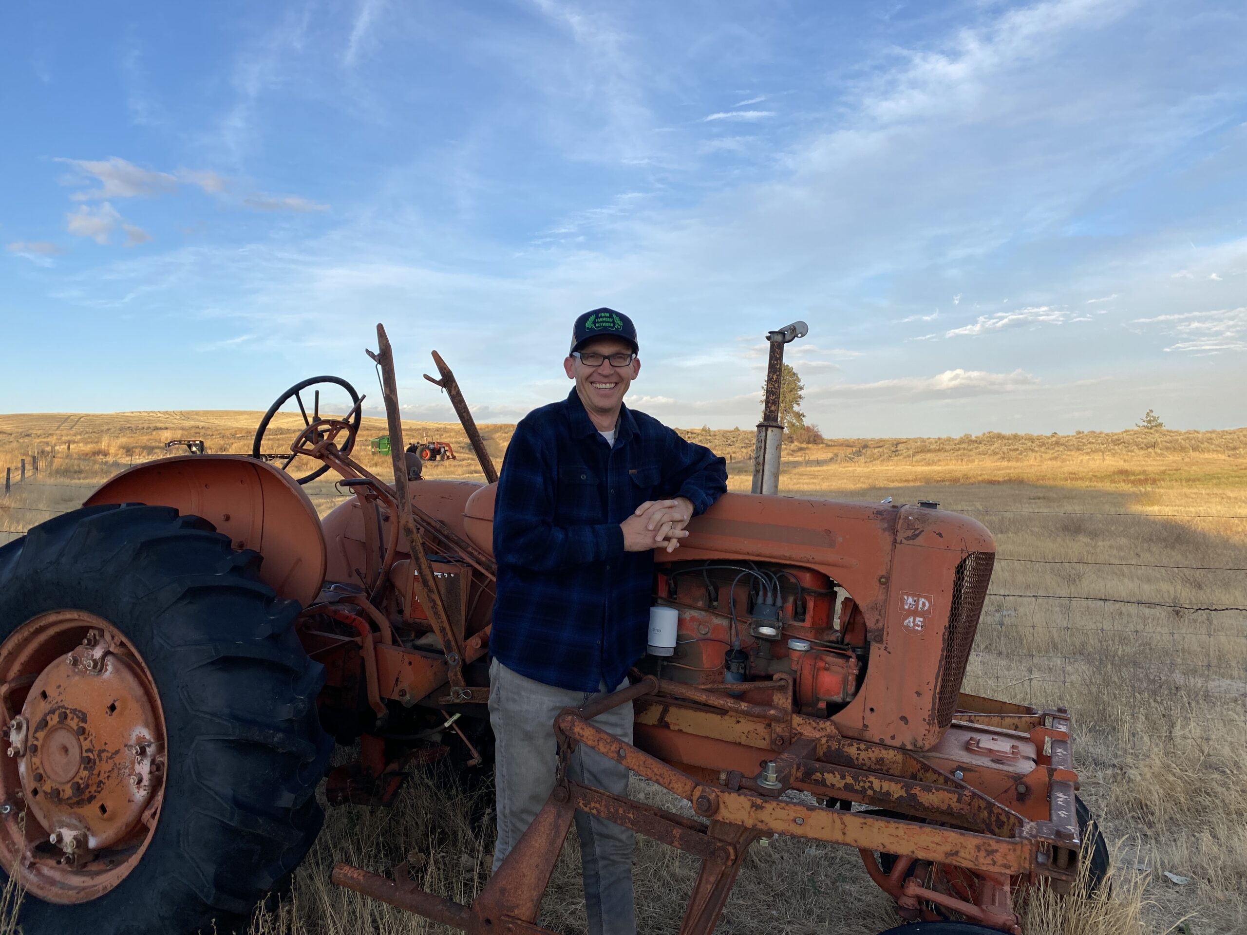 Jason Bishop in front of tractor and field.