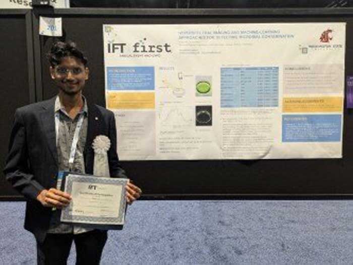 Rishabh Goyal holding an award in front of presentation board.