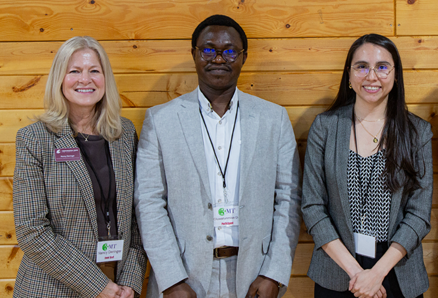 Three people standing together against a wall.