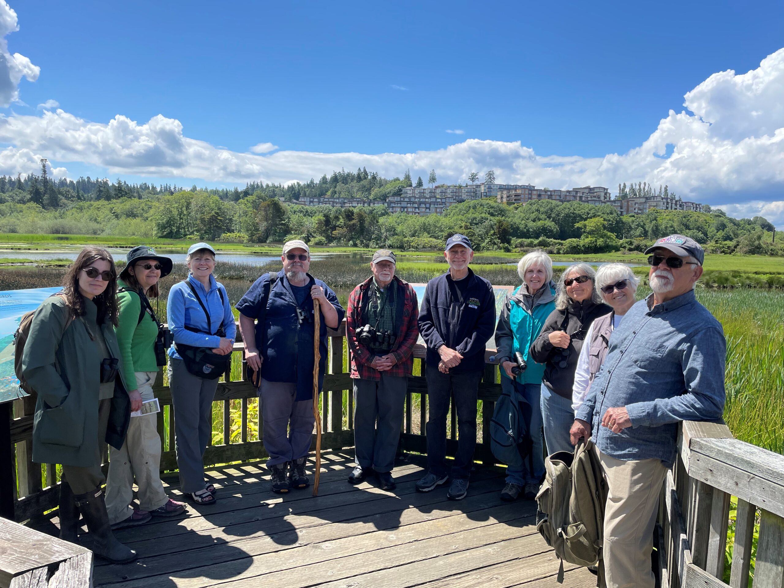 Group of smiling Washington State Naturalist participants on an elevated platform in an urban marsh in Edmonds, Washington.