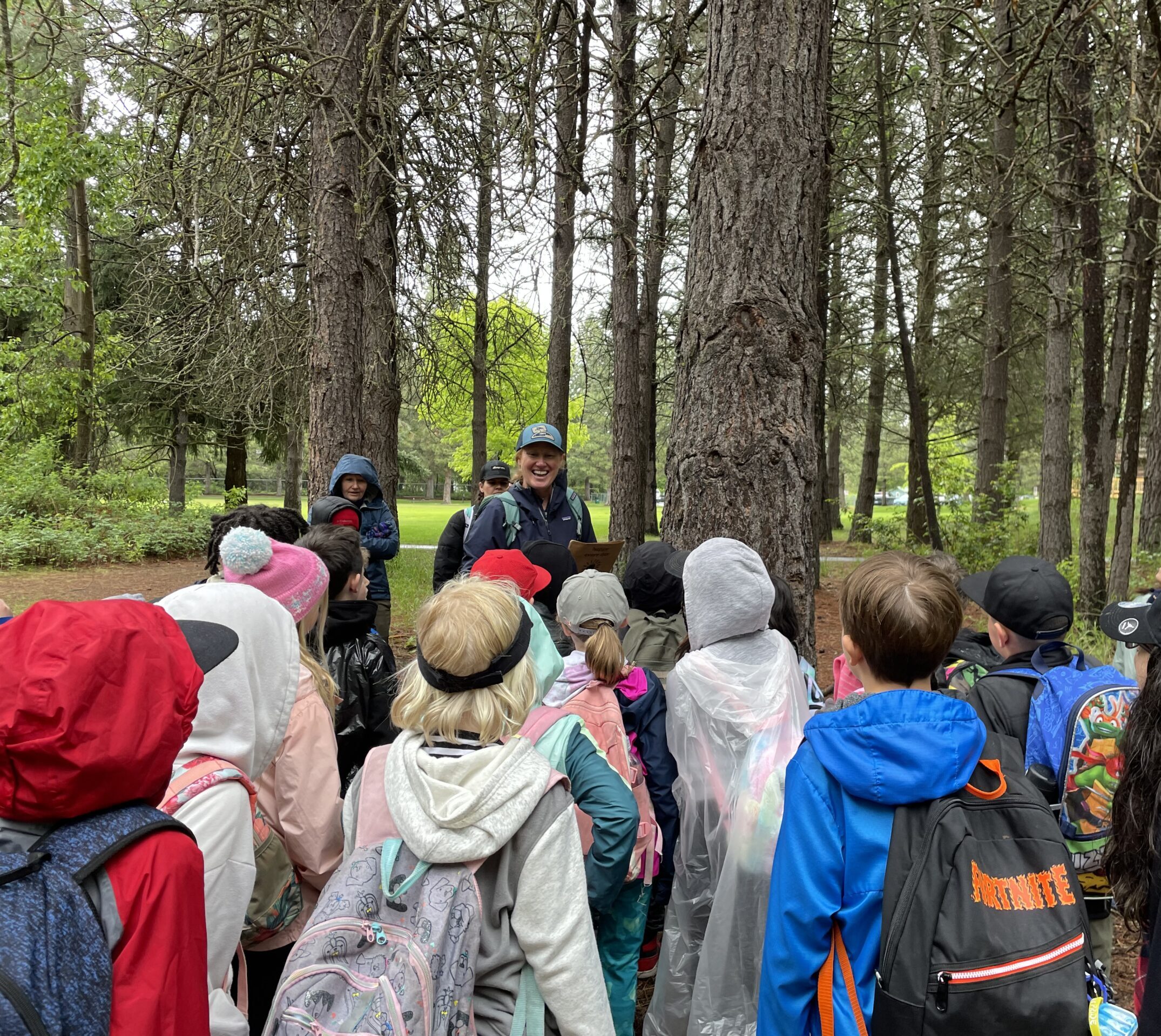 Several Washington State Naturalist volunteers surrounded by a group of children in the woods.
