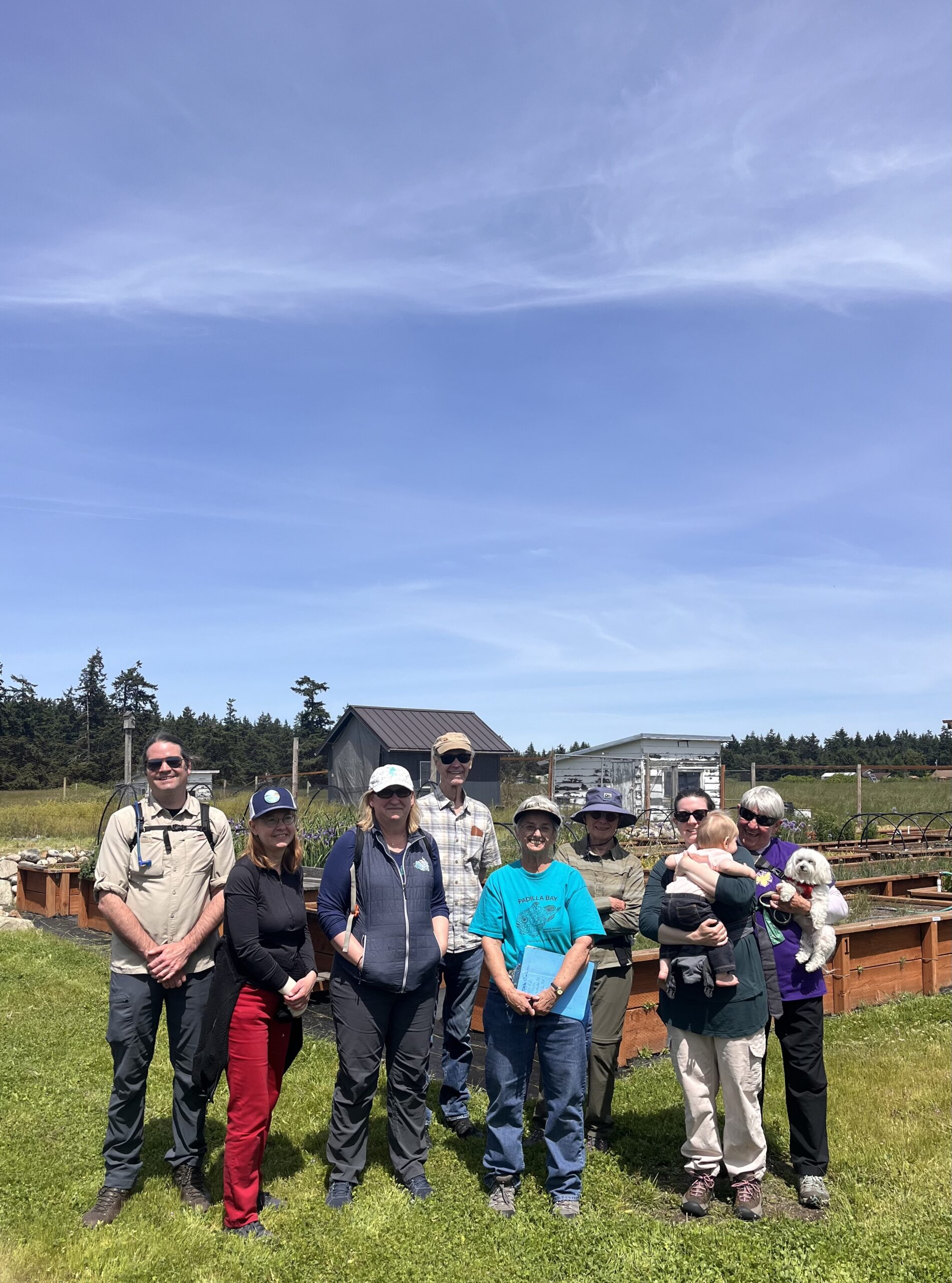 Group of Washington State Naturalist participants standing in front of raised beds and smiling.