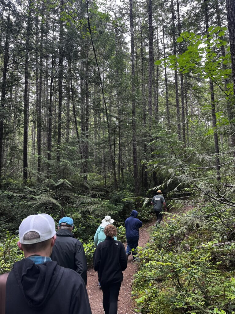 A line of Naturalists follow Gabriel Newton from Great Peninsula Conservancy through the forest at Ueland Tree Farm.
