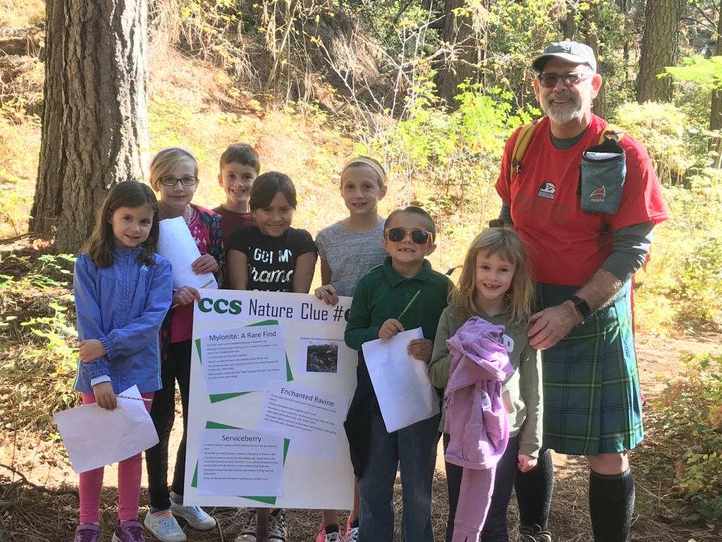 Group of children in outdoors gear standing in front of a map for Dishman Hills
