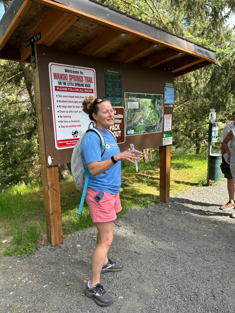 Volunteer Hike Docent, Alana Livingston in front of the Waikiki Springs trail head sign