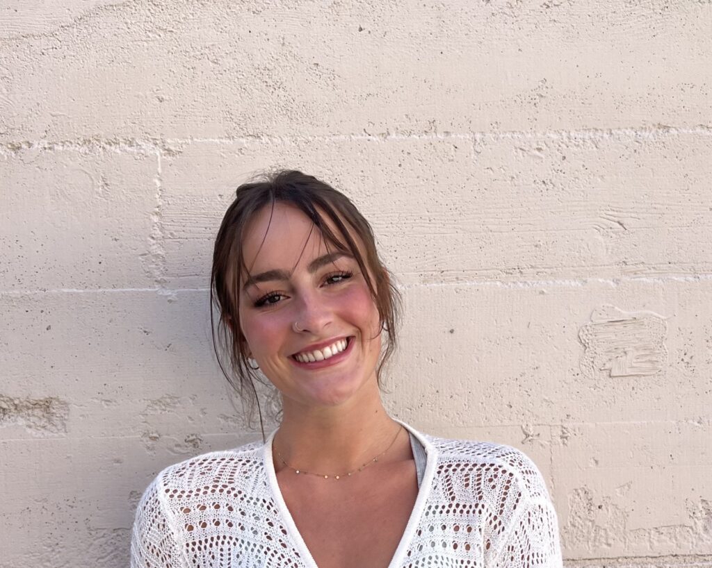 Woman smiling, standing in front of gray background