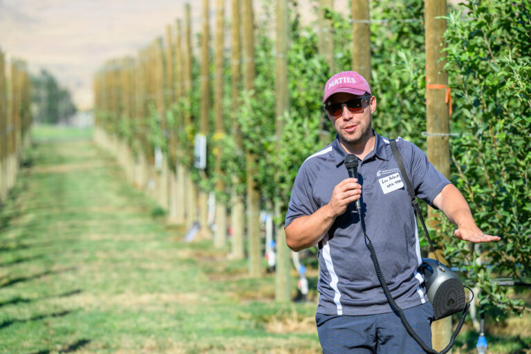 Lee Kalcsits walking through a row of an orchard. 