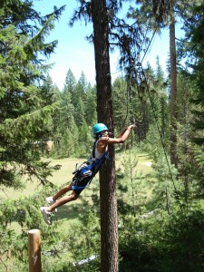 A ropes course participant swings on the trapeze about 20 feet off the ground at Camp Long in Seattle.