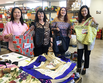 Three faculty members and a staffer show off colorful shopping bags at the food bank.