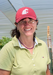 Portrait of Miles, in WSU red hat, at greenhouse