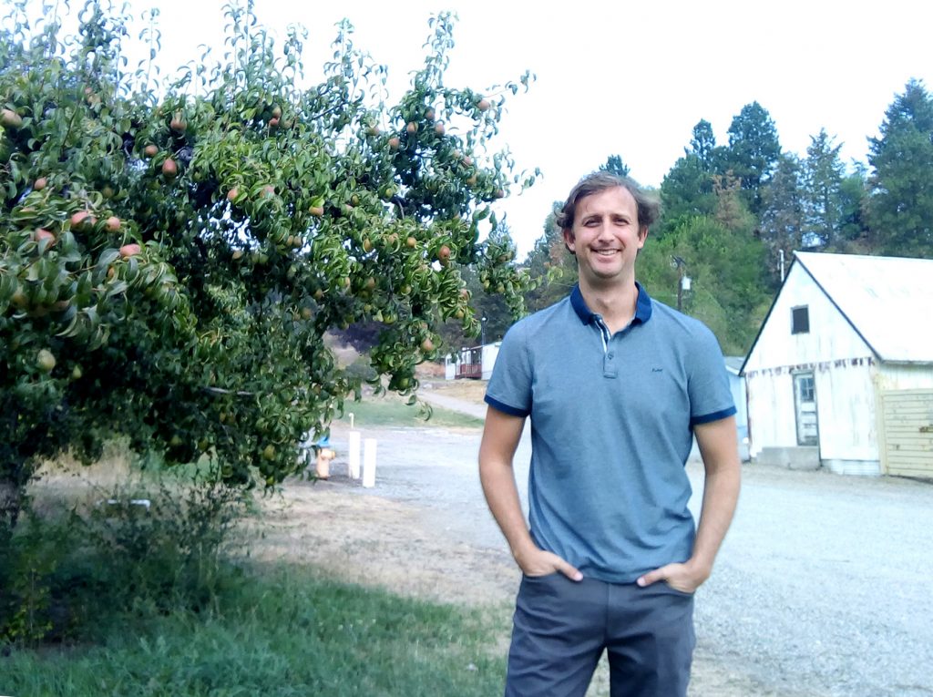 Tobin Northfield, outside at a research station, next to apple trees.