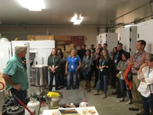 Walsh, left, faces about 25 visitors across the floor of an equipment-filled room.