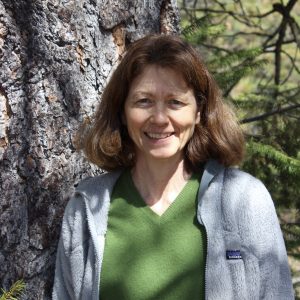 Profile photo of Marcia Ostrom outdoors near a tree.