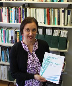Golberger, in front of wall of books, holding a journal.