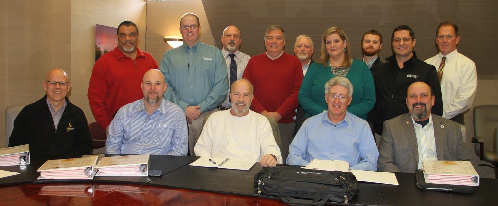 Group, posed photo of commission members and staff with WSU faculty in board room, one row standing, one row sitting.