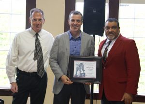 Group photo at awards ceremony; Collins holds award.