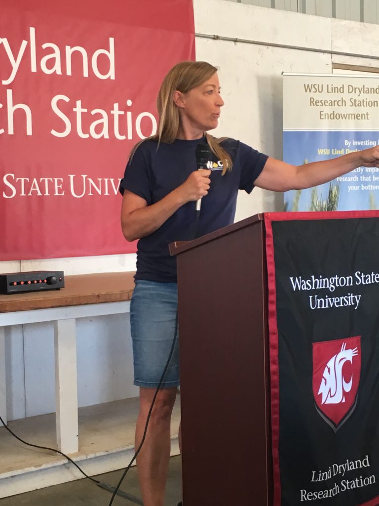 Karen stands and gestures at the podium.