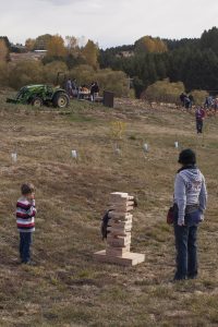 A little boy and his mom stand next to a tall stack of wooden blocks.