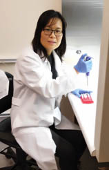 Ying Zhai, seated, working in lab.