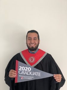 Garcia holds a pennant saying "2020 Graduate" while wearing formal graduation robes.