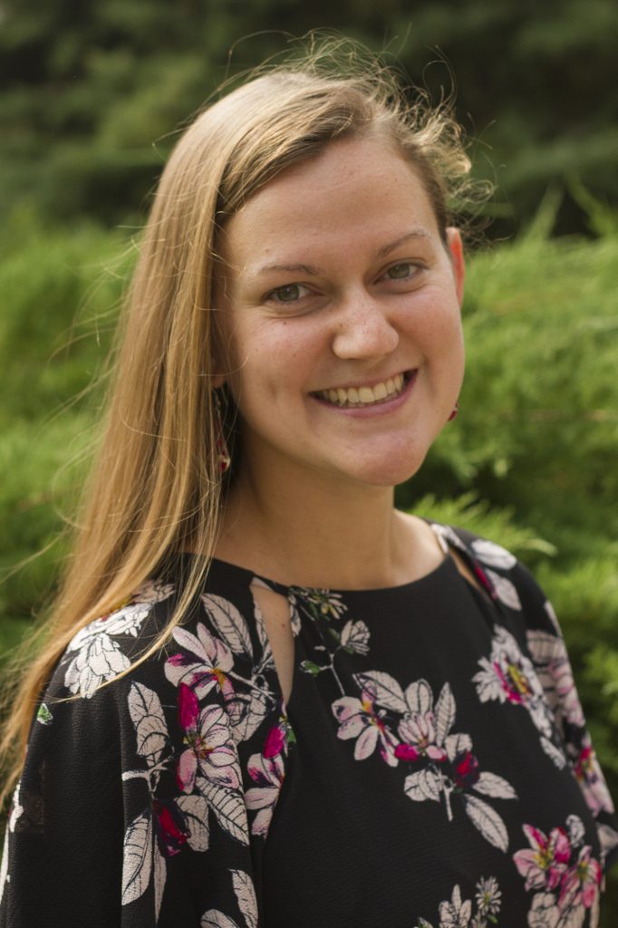 Formal portrait photo of Raven Weaver, taken outside with greenery in the background.