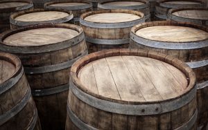 Wood wine barrels are packed together in a wine cellar.