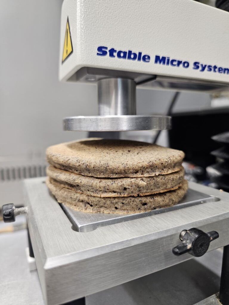 A stack of 3 pancakes on what looks like a metallic press.