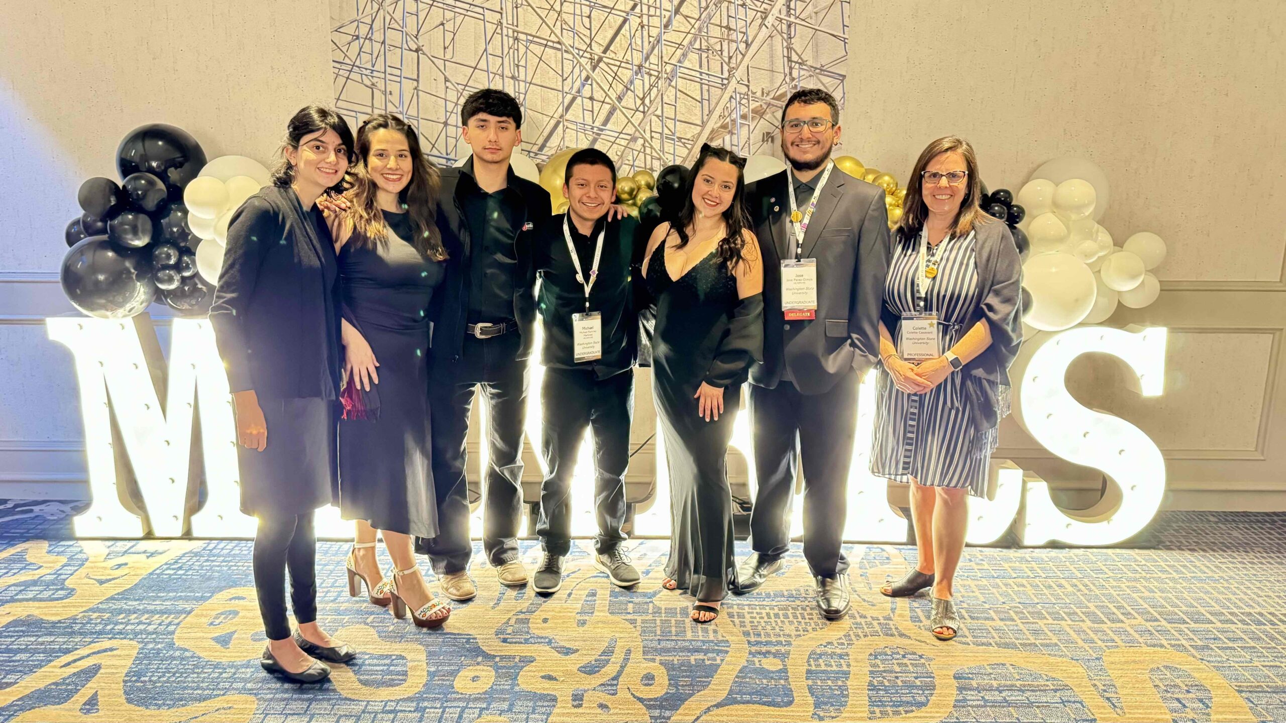 A group of seven people, stand in front of MANRRS sign.