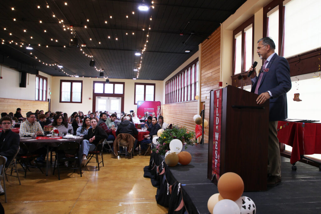 Dean Khosla speaks at a podium to people seated at round tables in Ensminger Pavilion.