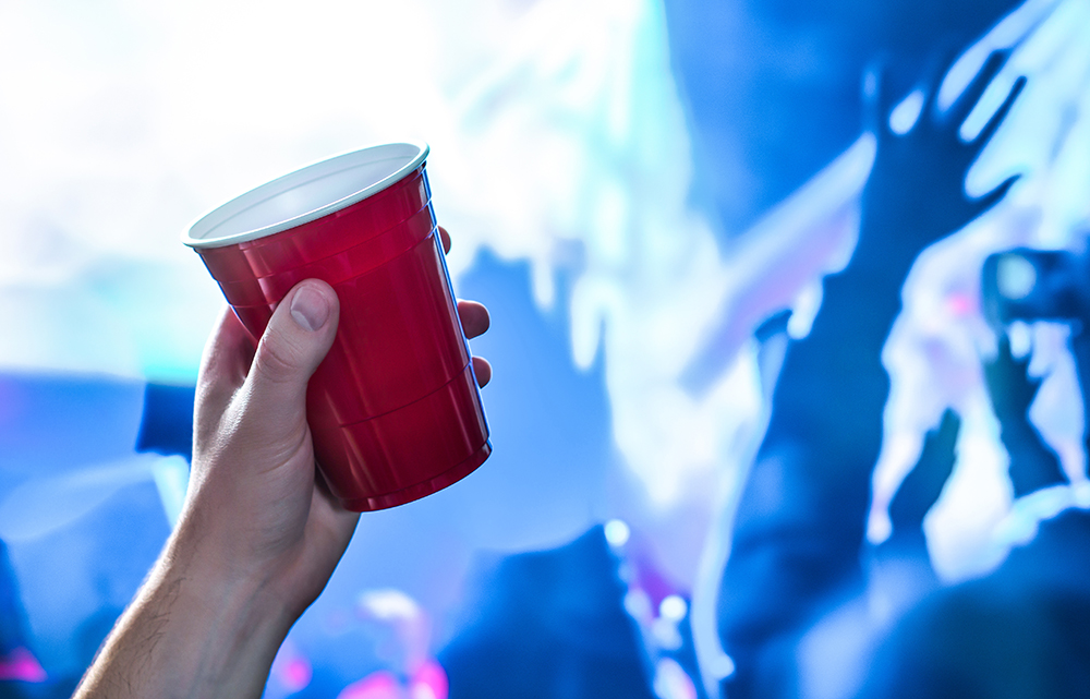 Red party cup in hand in night club, bar, or college student event.