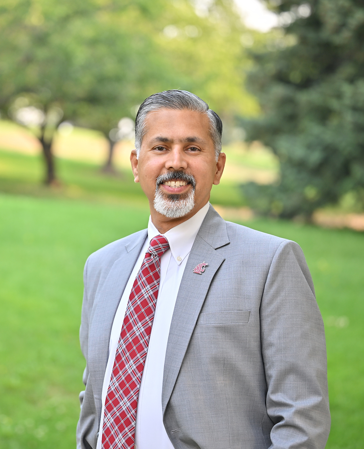 Raj Khosla pictured in suit and tie in green parklike setting