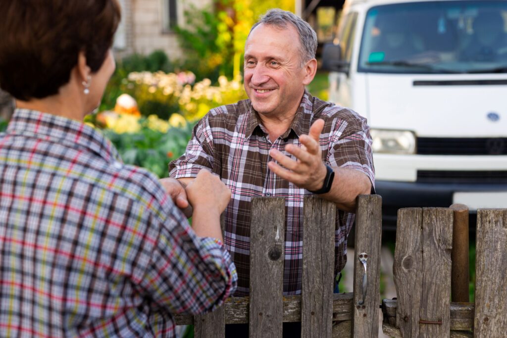 Person speaking across the fence with a neighbor.