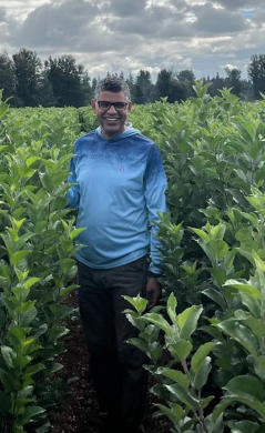 Dipak Poudyal, standing in a field of apples.