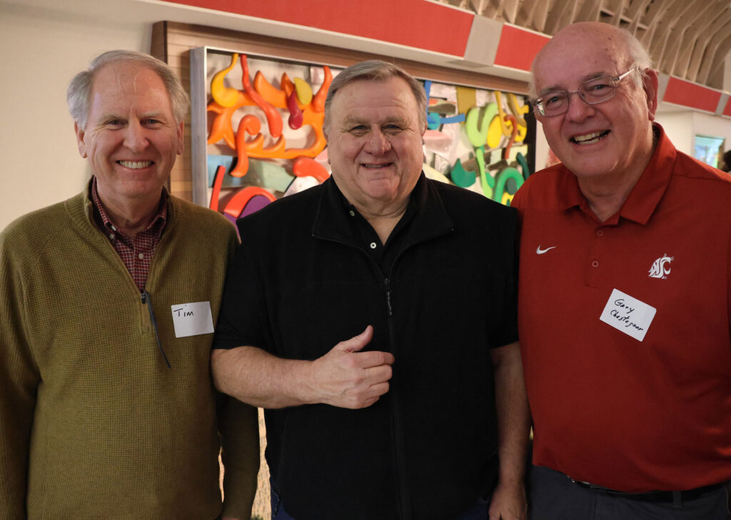 Three men stand together. The one on the left has a name tag that says "Tim." The one on the right has a name tag that says "Gary Chastagner."
