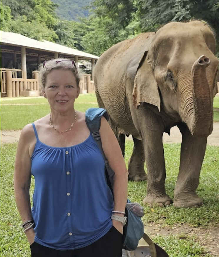 A woman stands next to an elephant.