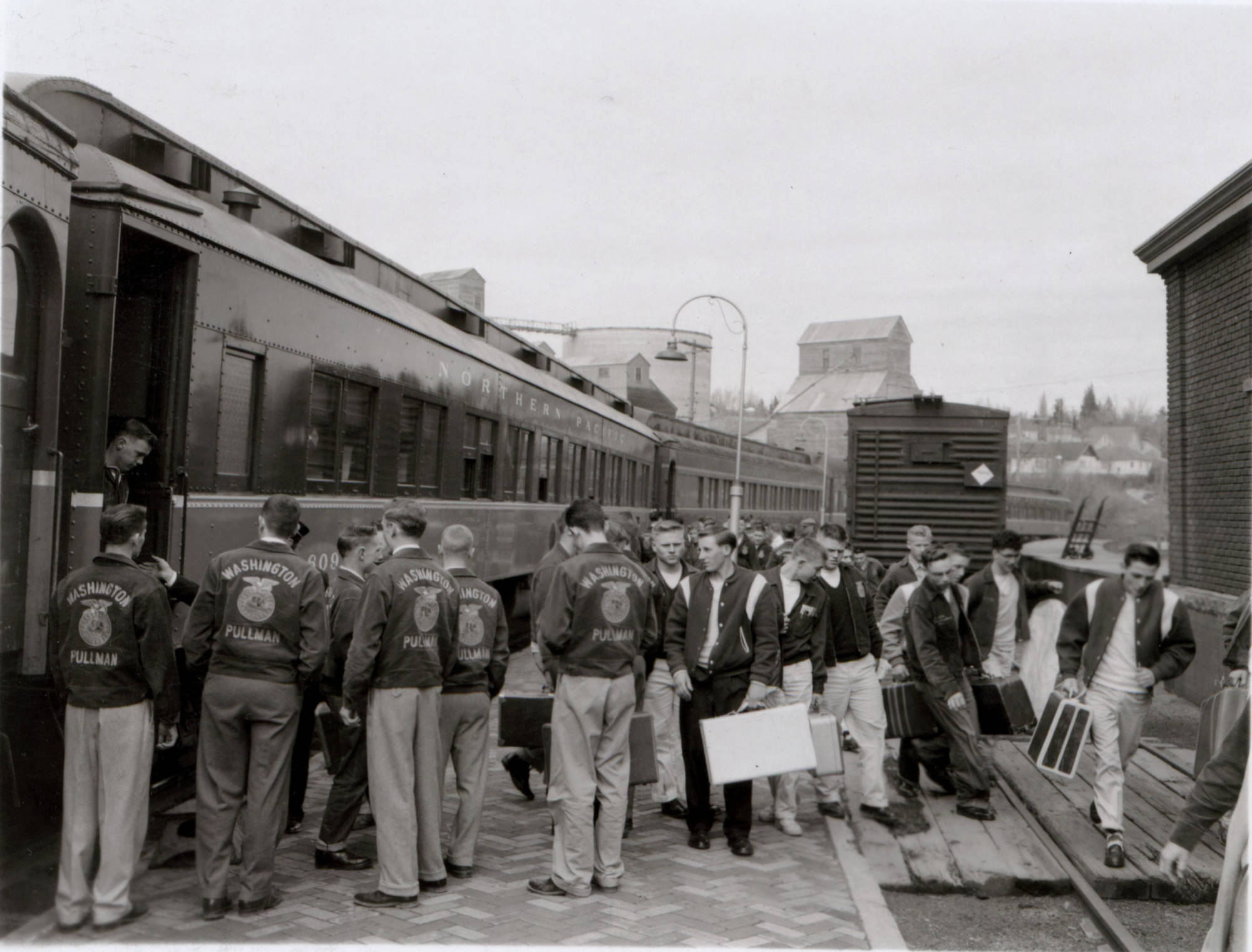High school students disembark from a Northern Pacific train at the Pullman depot for the four-day 25th state Future Farmers of America convention, held WSC, 1956.