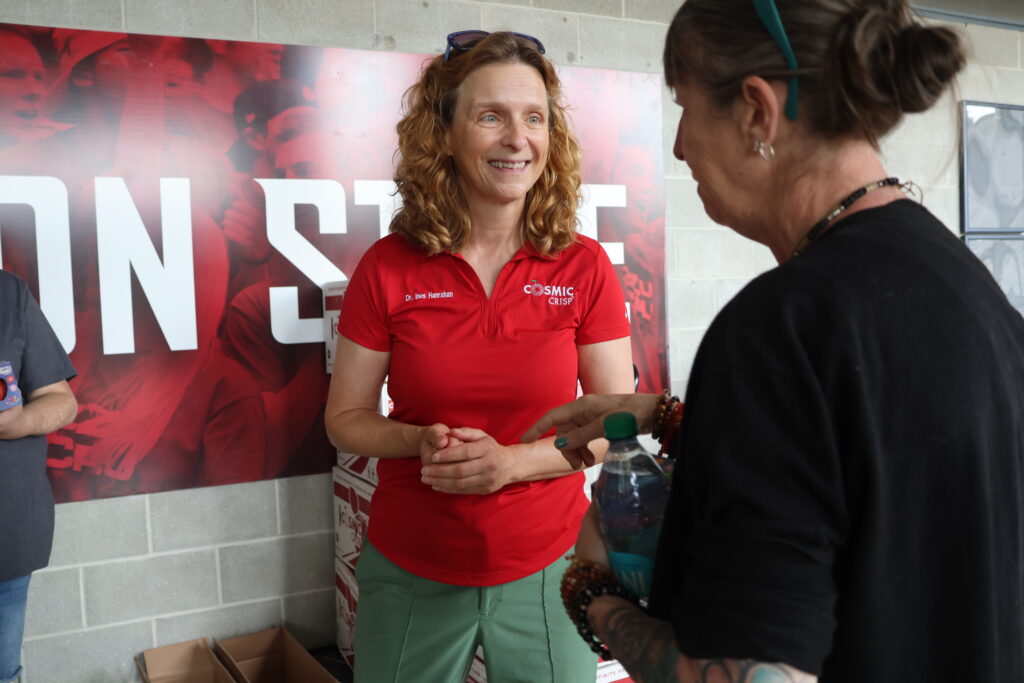 Ines, center, smiles while interacting with a woman standing in front of her.