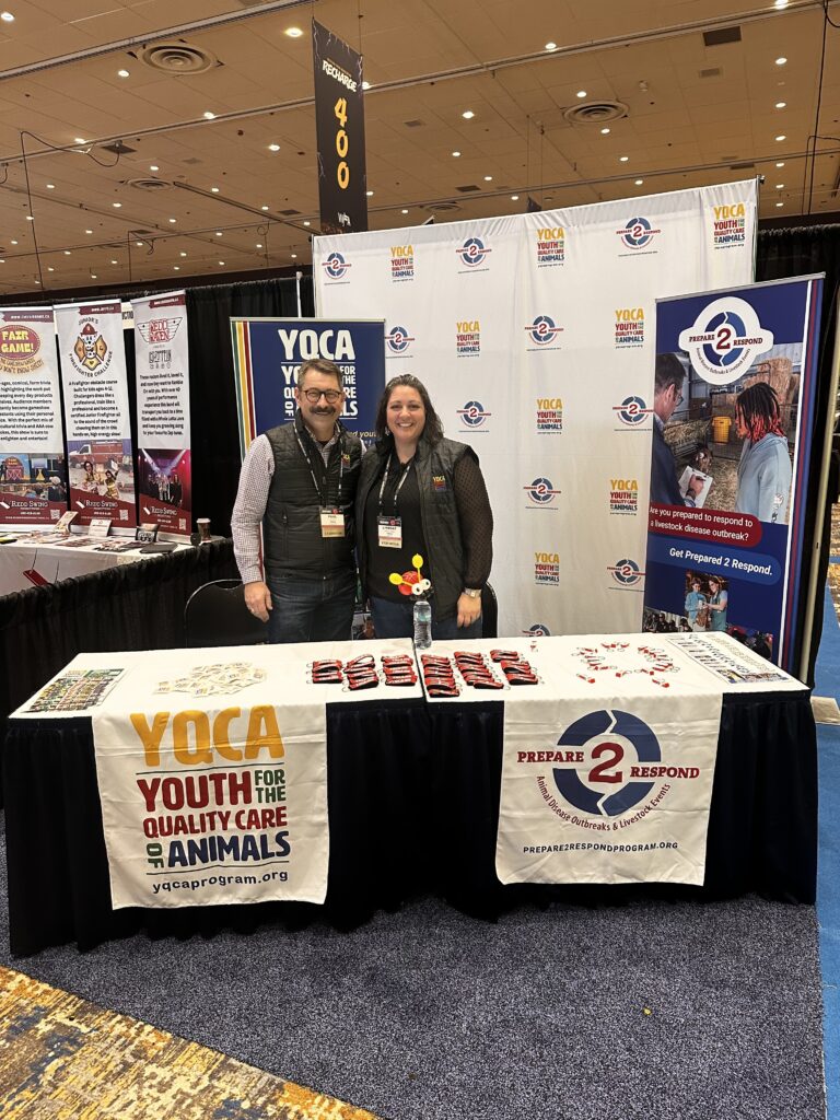 Paul Kuber stands next to someone at a Youth for the Quality Care of Animals booth.
