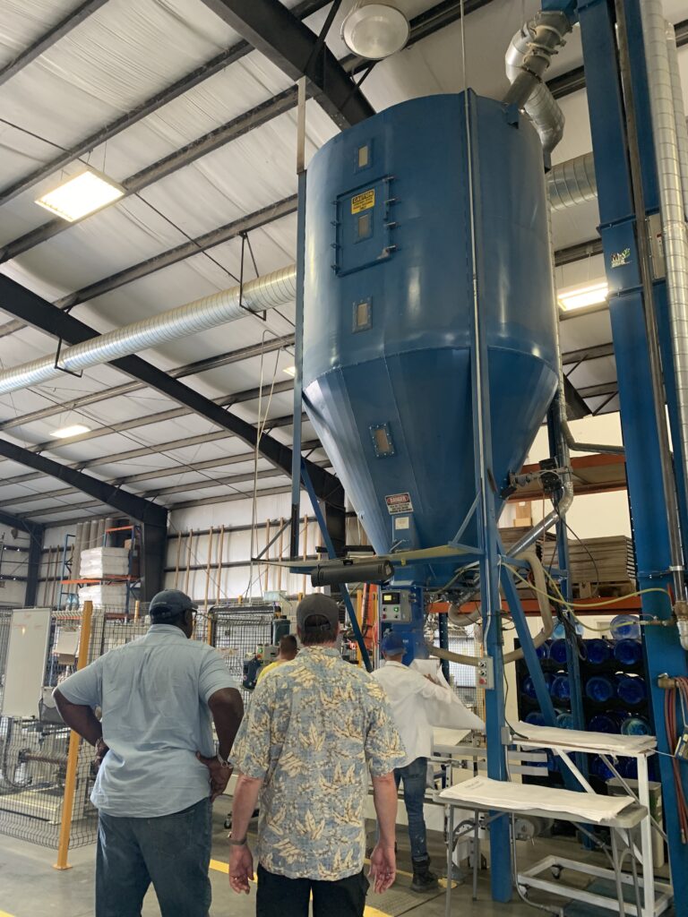 2 people face away from the camera as they look at a large piece of industrial machinery.