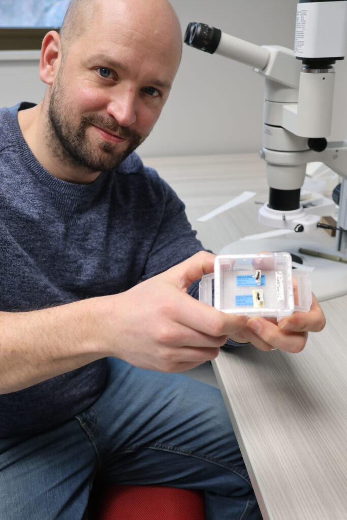 SIlas holding boxed bee specimens in lab