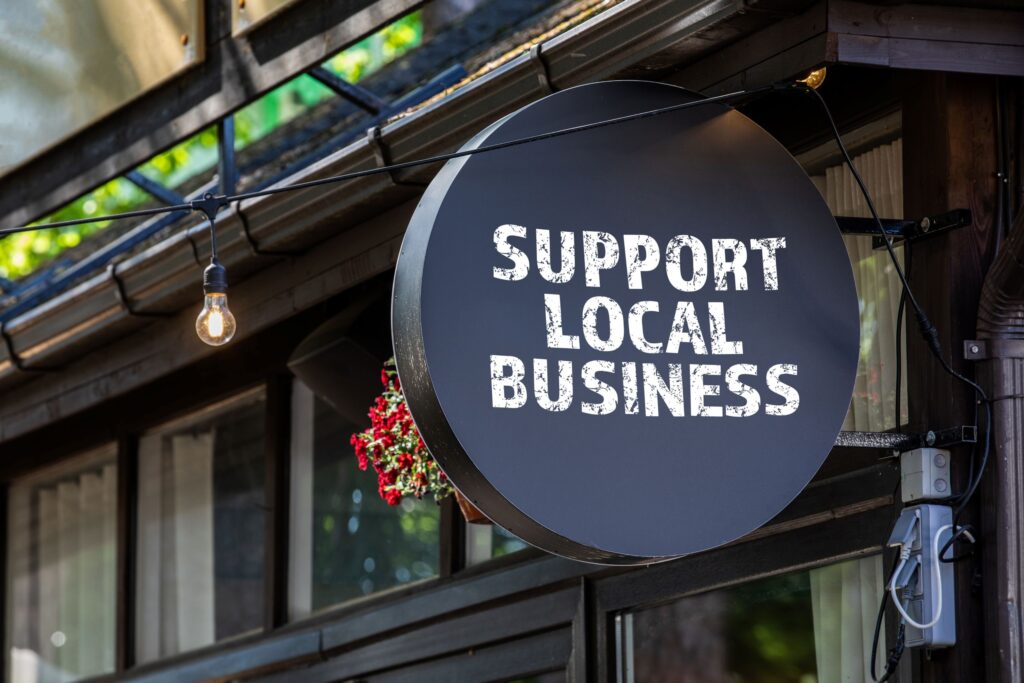 Round, black "Support Local Business" sign outside storefront. By STOATPHOTO on Adobe Images.