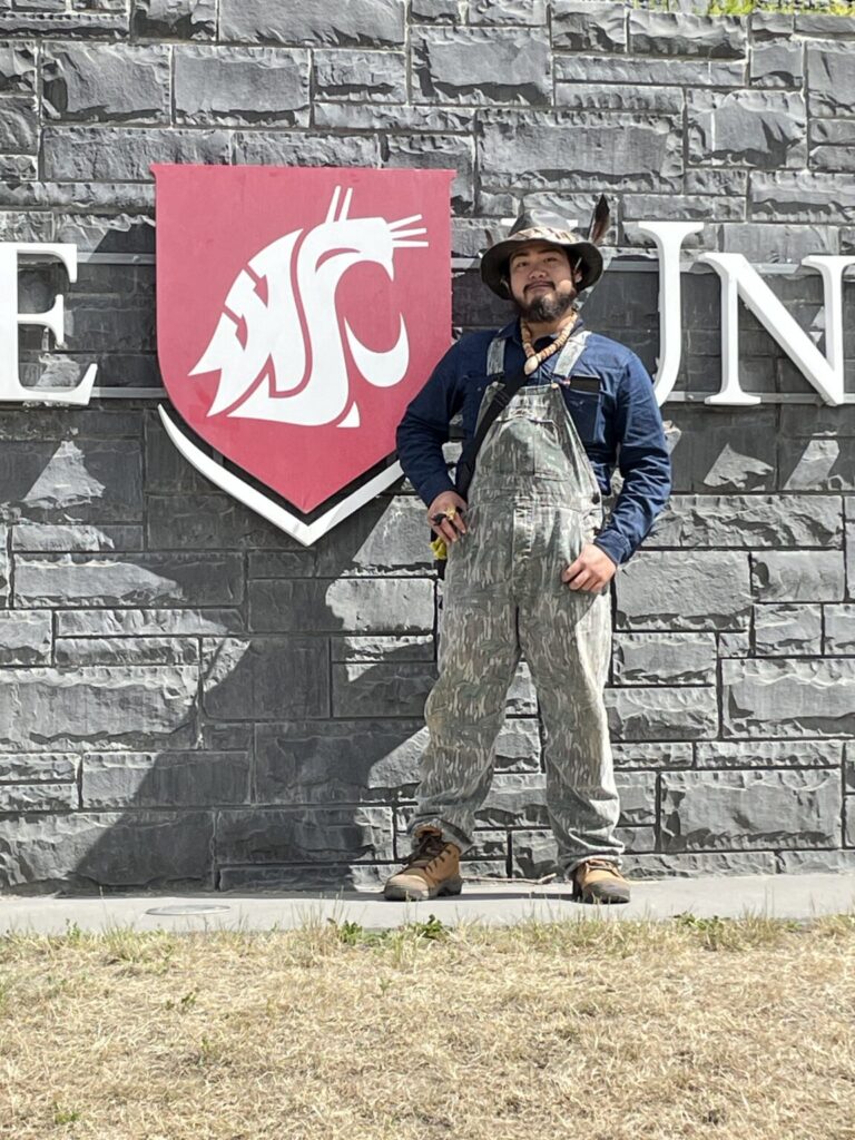 A person stands next to a WSU logo sign.