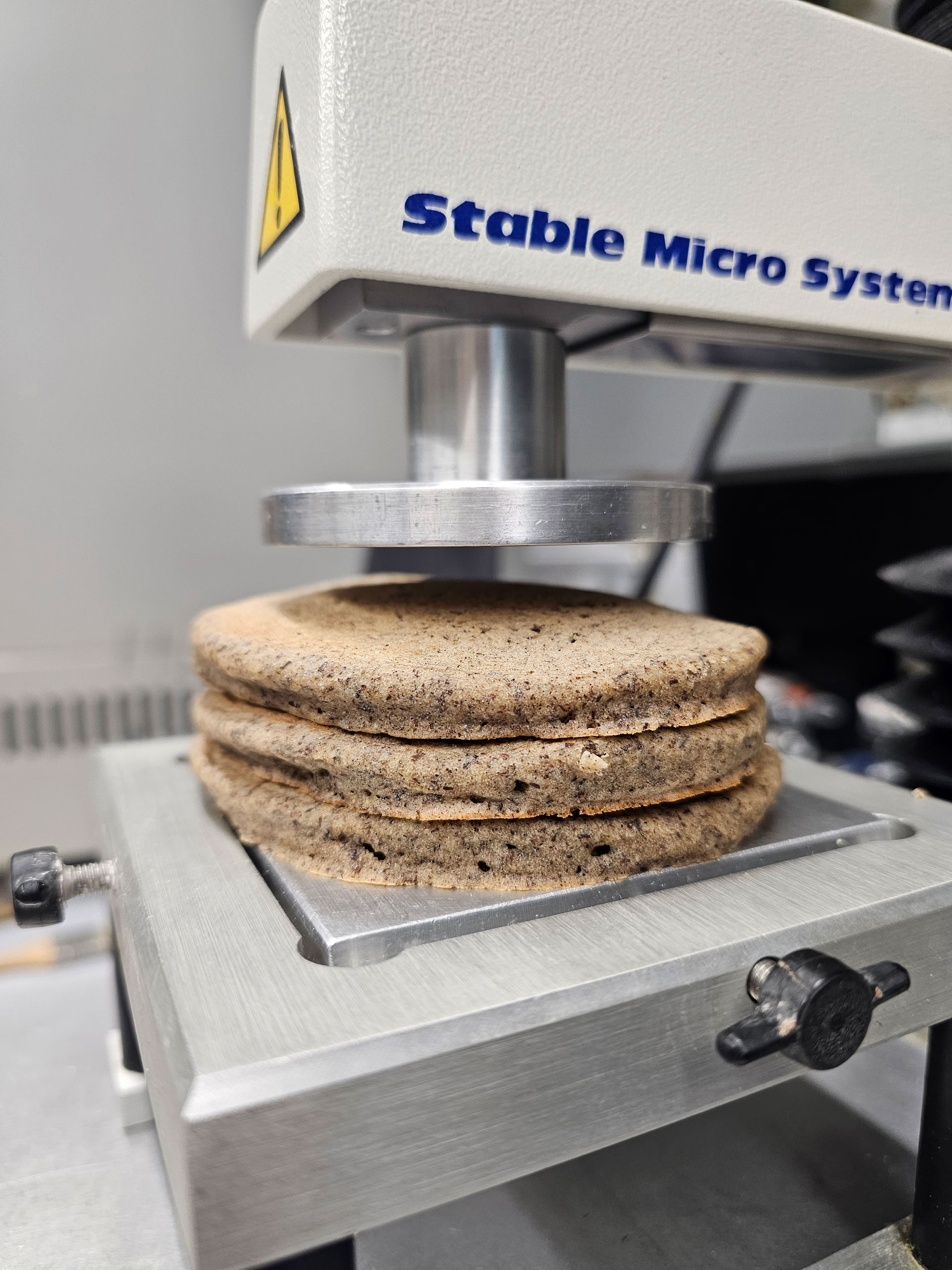 A stack of 3 pancakes on what looks like a metallic press. 