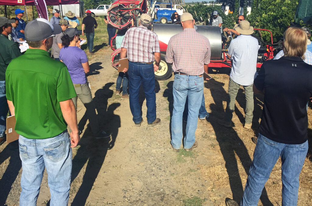 A group of tree fruit growers attend an outdoor WSU Extension workshop.